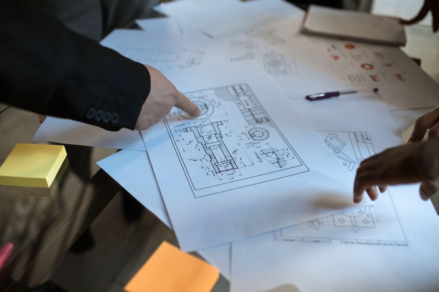 Hands reviewing dimensions and details on printed construction plans